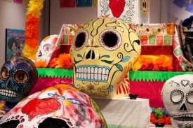 Large, brightly-color skull sculpture sits in front of an altar